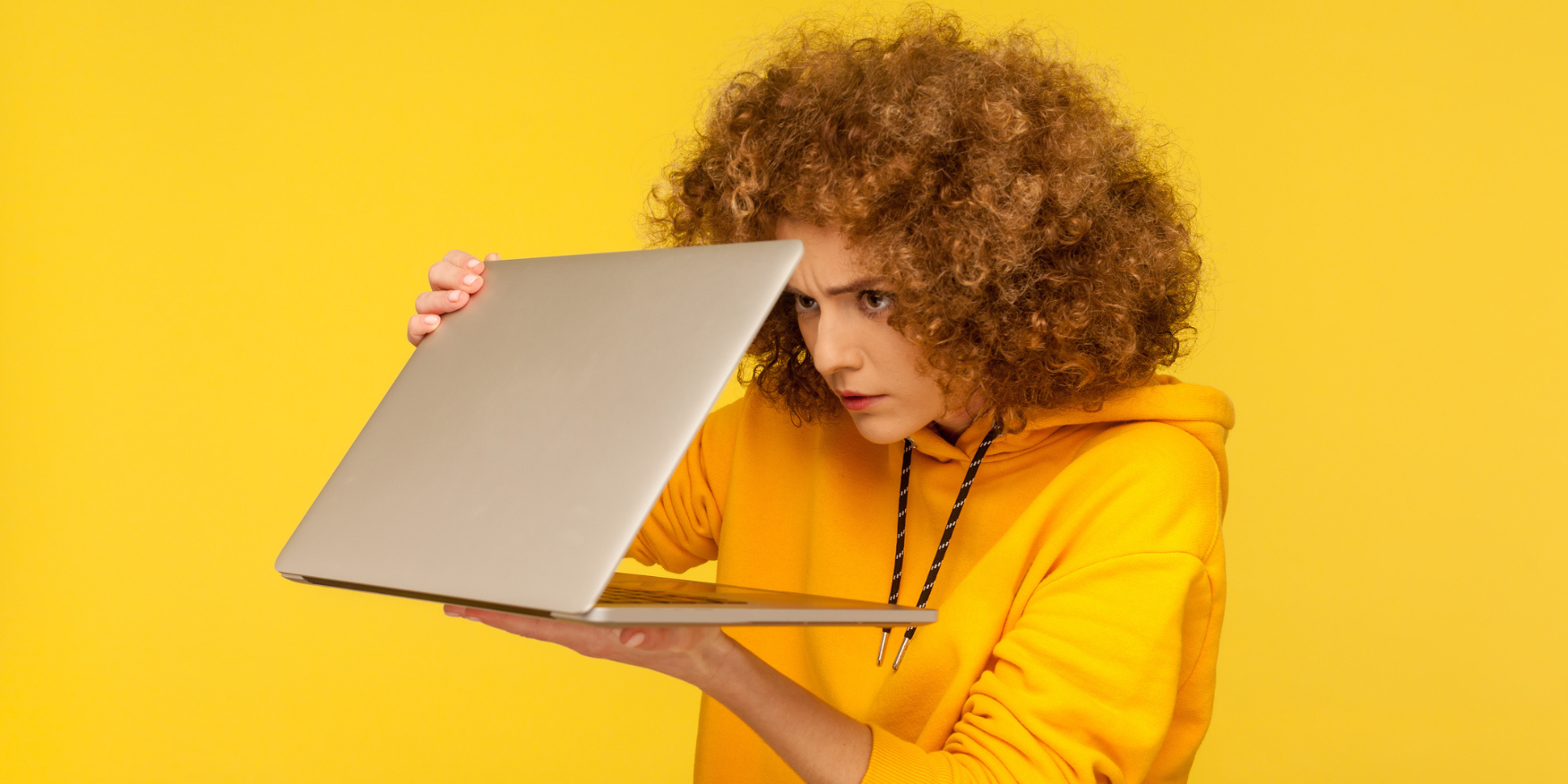 Woman in a yellow shirt carefully opening a laptop